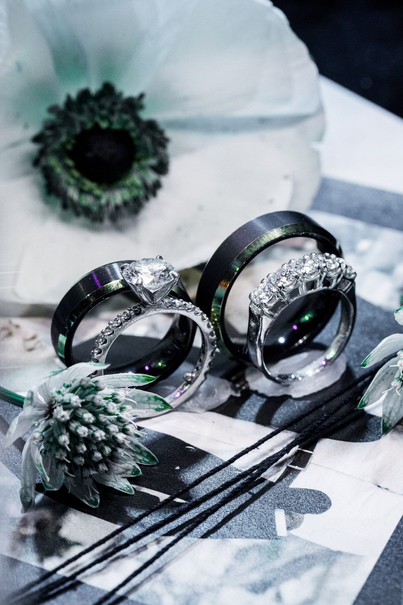Wedding rings resting on stationery beside an anemone