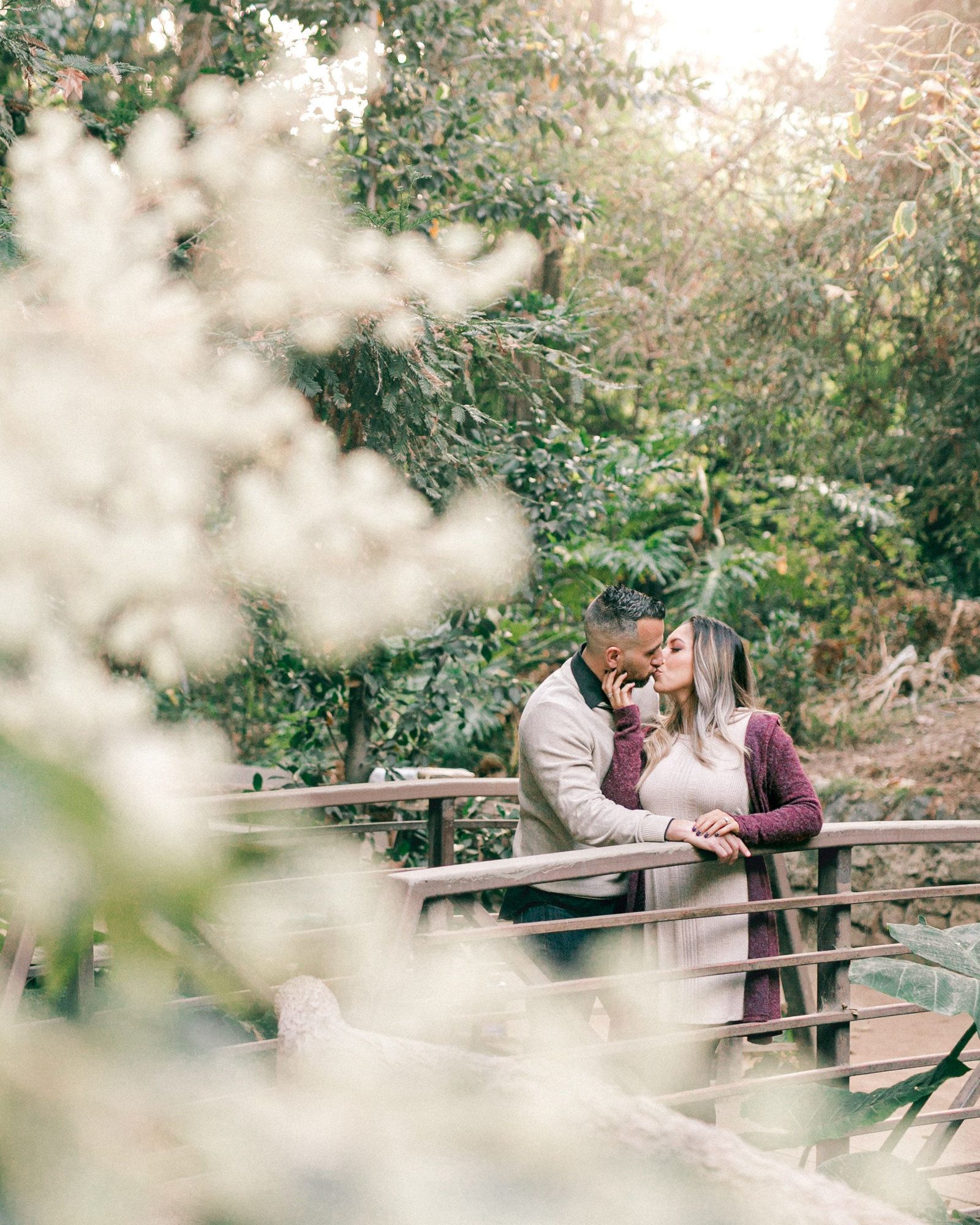 Couple on a wooden bridge framed by blossom