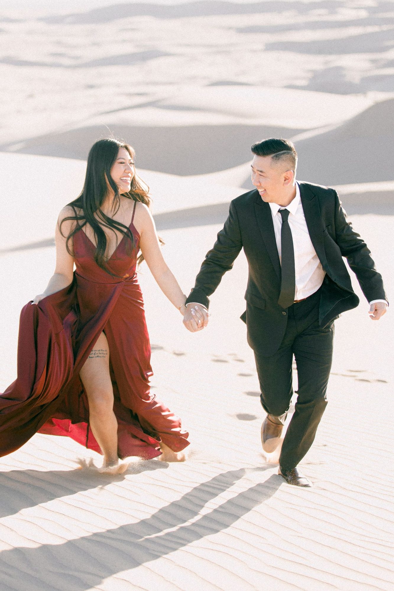 Couple walking hand in hand across the Glamis dunes