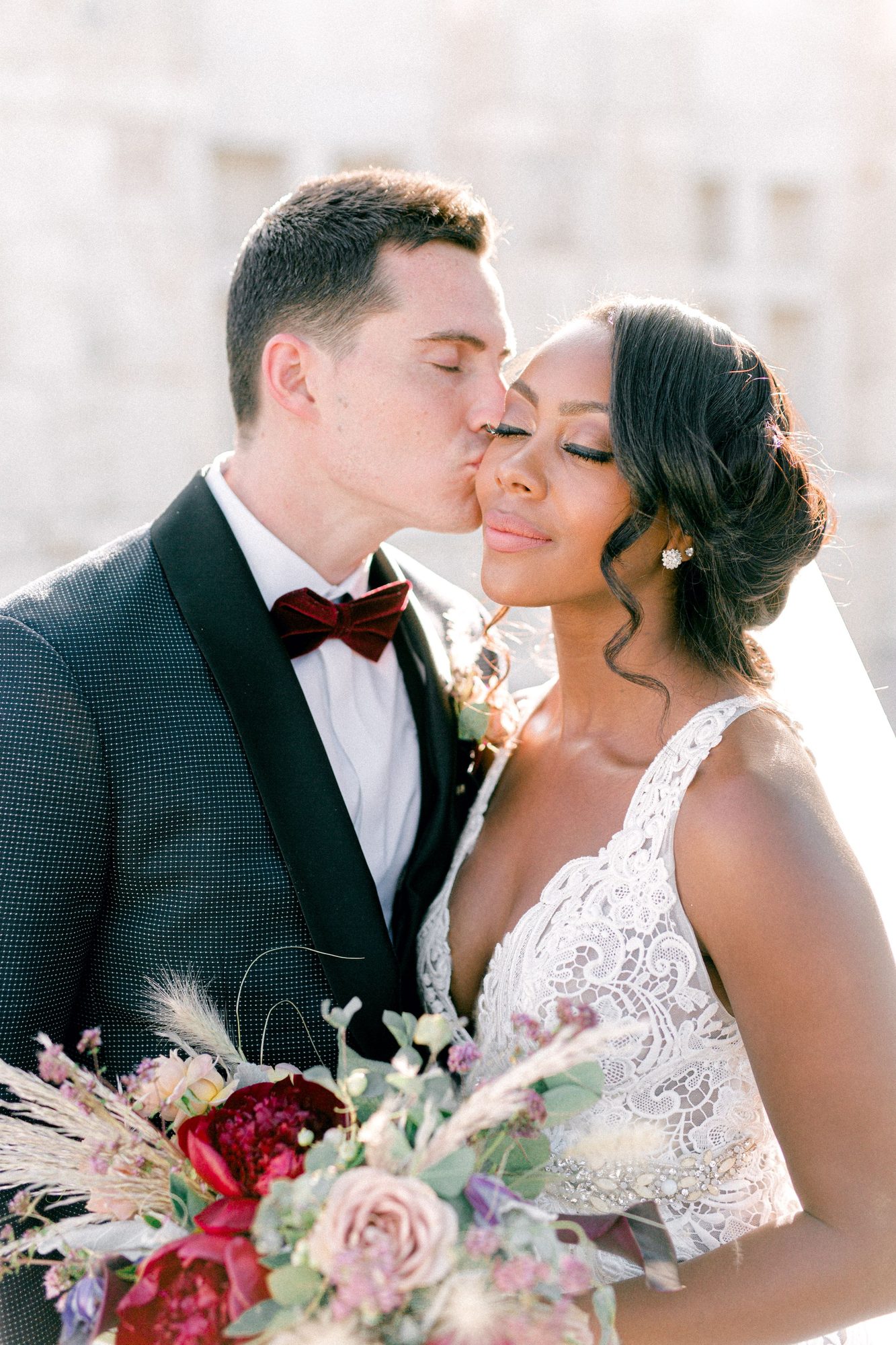 Cheek kiss with a burgundy and blush bouquet