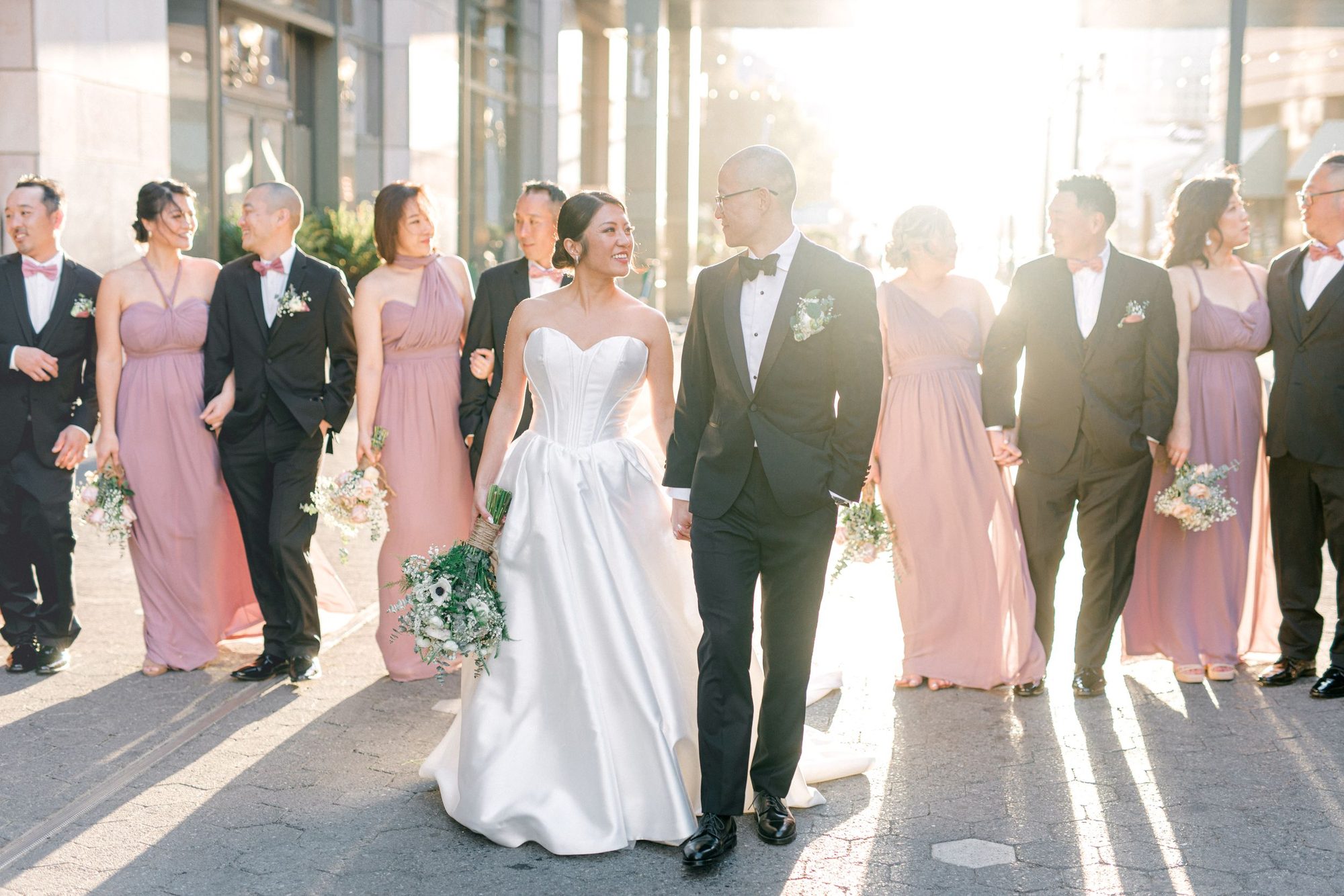 Bride and groom walking with their bridal party in afternoon sun