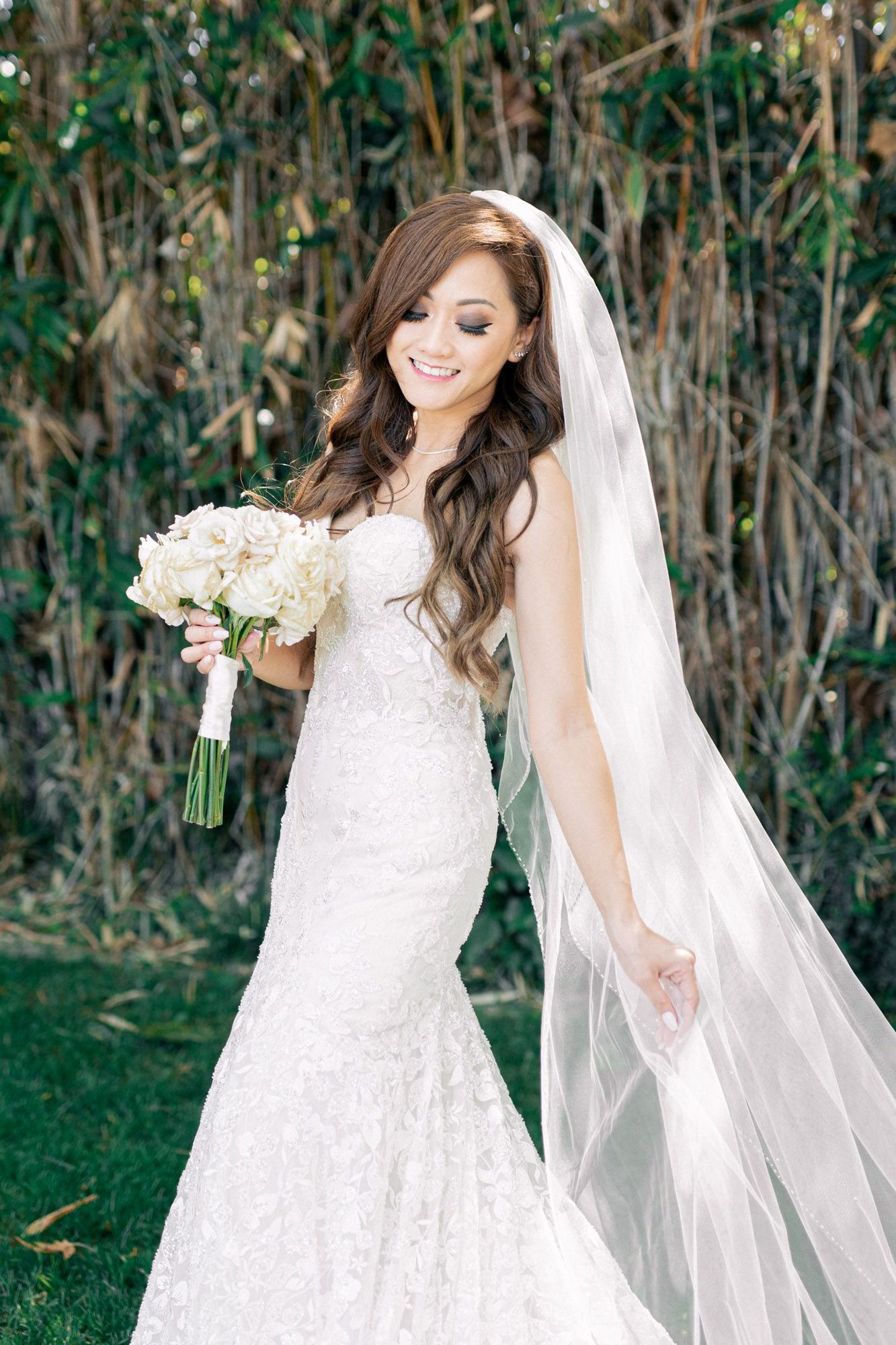 Bride with a long veil against greenery