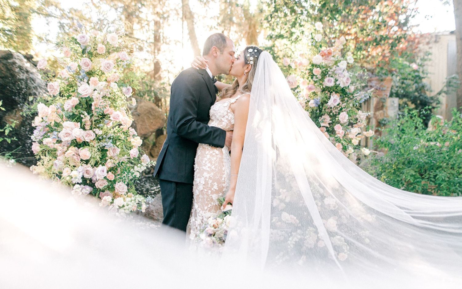 Kiss among climbing roses with the veil in the foreground