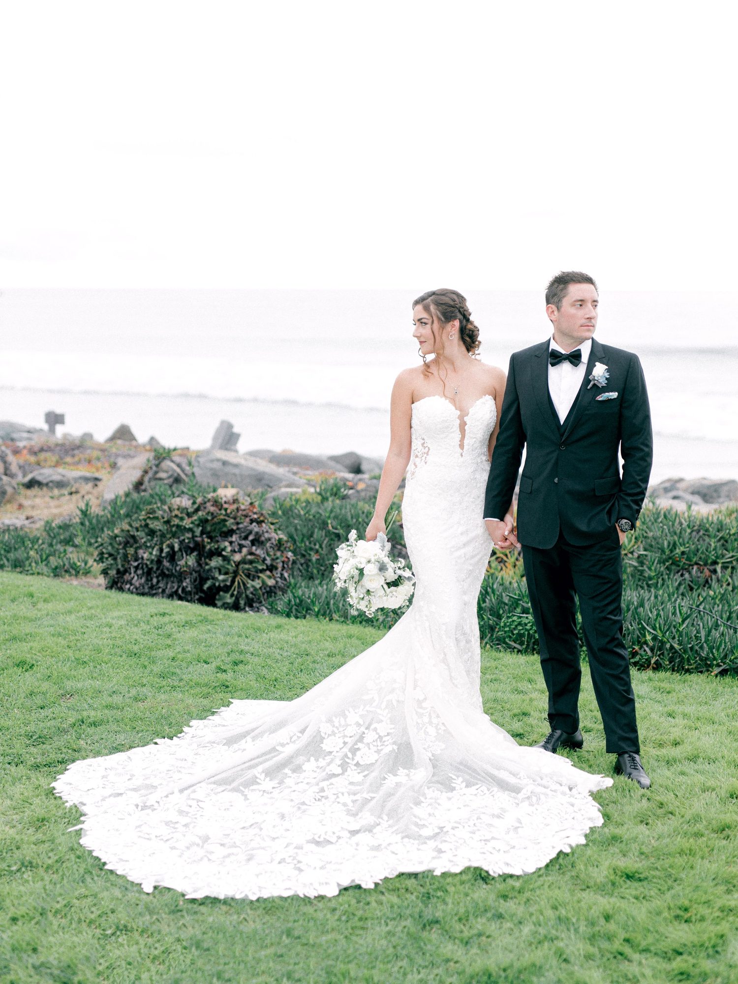 Couple on a coastal lawn, the dress train spread on the grass