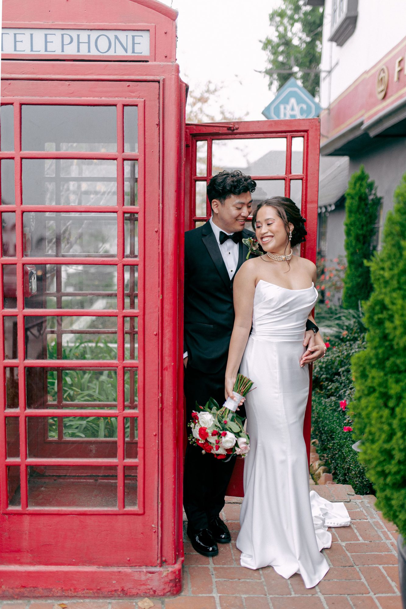 Couple laughing in the doorway of a red telephone box