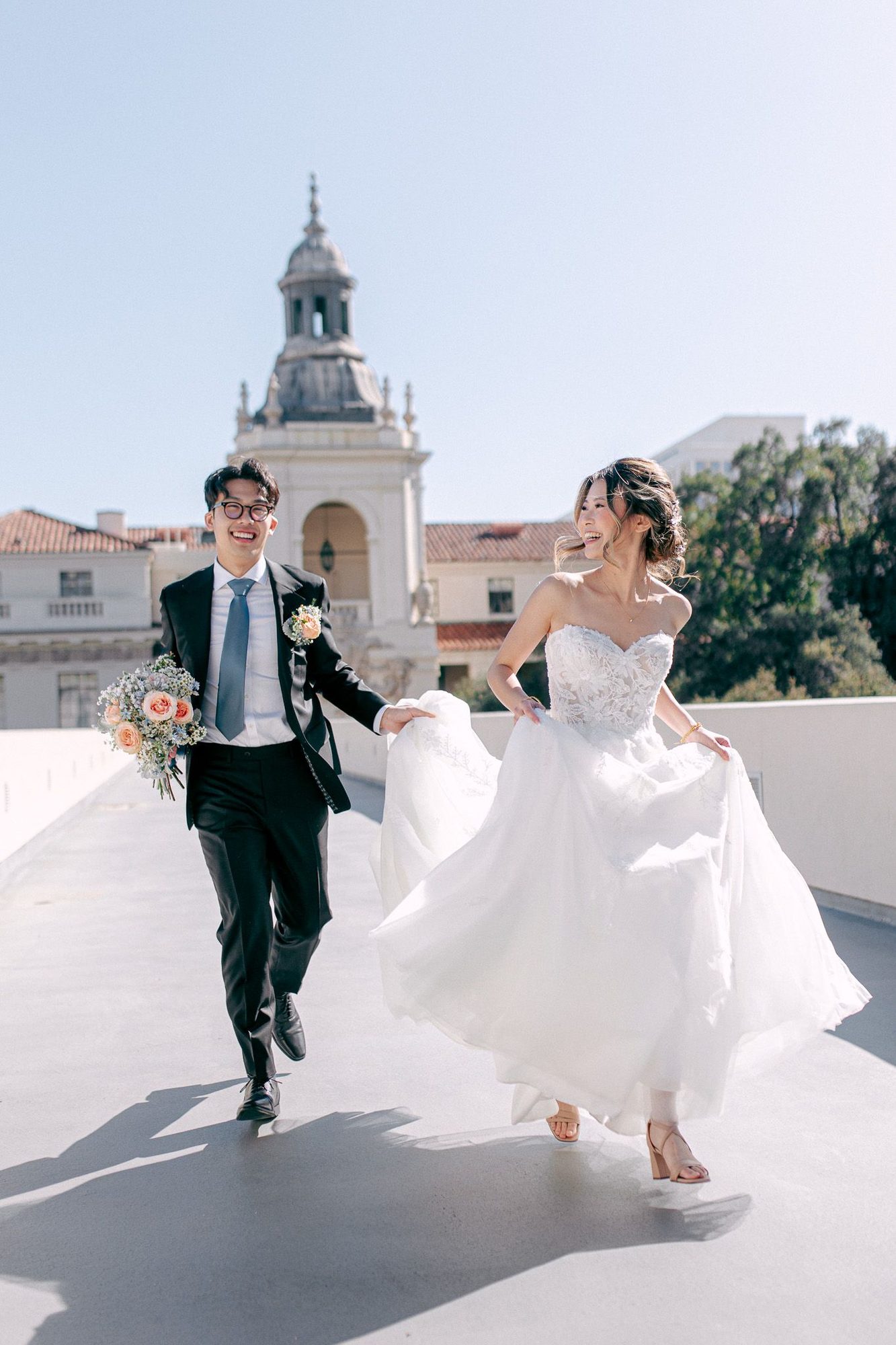 Couple running and laughing, a white tower behind them