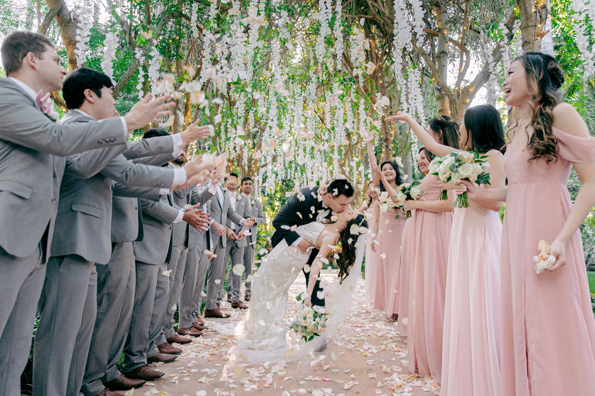 Bridal party lining a tunnel of hanging flowers