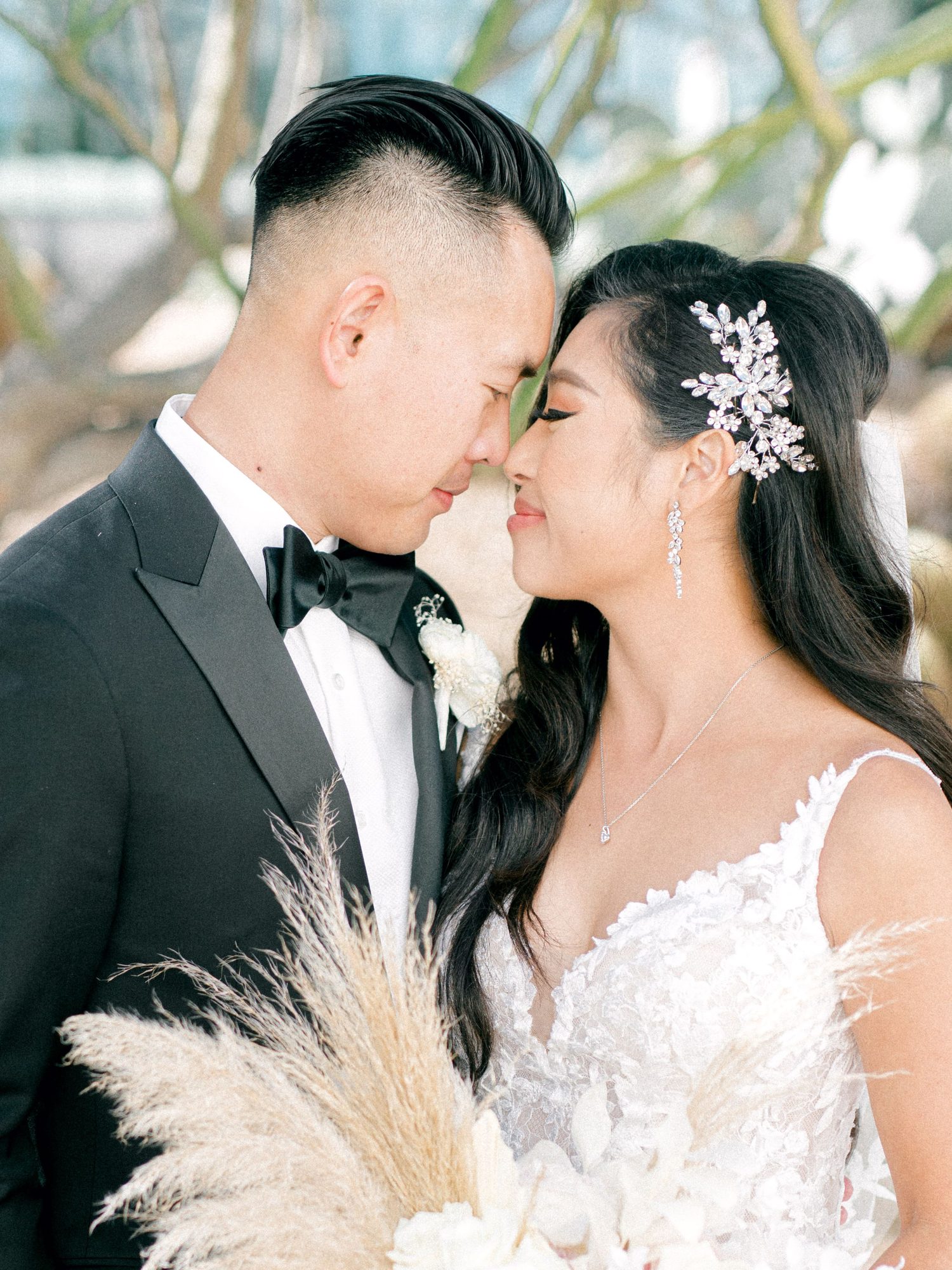 Couple touching foreheads, pampas bouquet in front